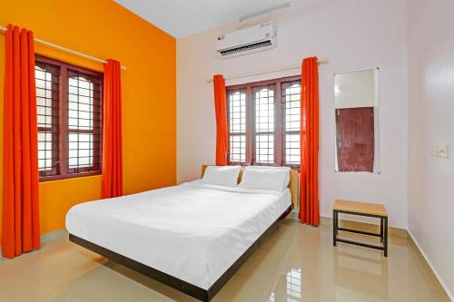 a bedroom with orange curtains and a large bed at Capital O Pop Tavern Kazhakkottam in Trivandrum