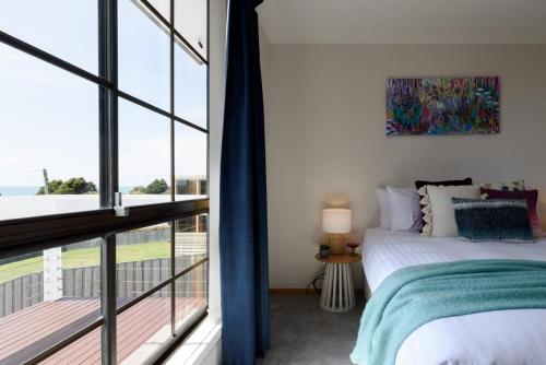 una camera da letto con un letto e una grande finestra di Ocean View Retreat at Greens Beach a Greens Beach
