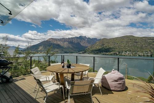 a wooden deck with a table and chairs and mountains at Charming Lakeview Home with Remarkable Views in Frankton Wharf
