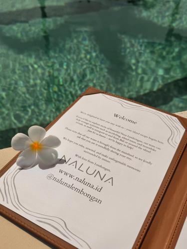 a white flower sitting on top of a menu at Naluna Lembongan in Nusa Lembongan