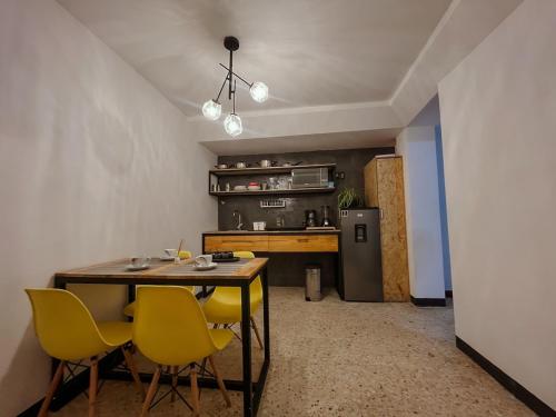 a kitchen with a dining table and yellow chairs at Two-bedroom apartment with AC in the center Oaxaca in Oaxaca City