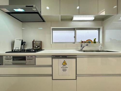 a kitchen with a sink and a counter with a microwave at nestay villa tokyo itabashi in Tokyo