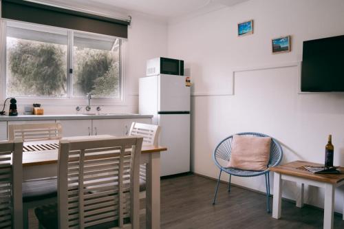 a kitchen with a table and a refrigerator at Busselton Jetty Chalets in Busselton