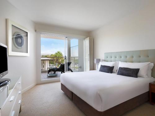 a bedroom with a large white bed and a balcony at Mantra on Salt Beach in Kingscliff