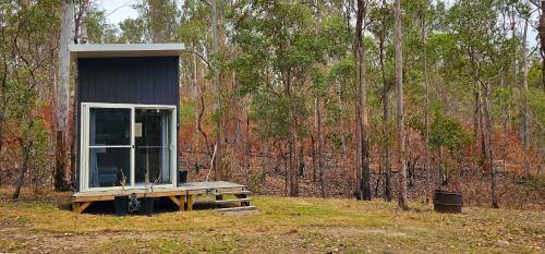 a small cabin in the middle of a forest at Hidden Camp's Loft House by Tiny Away in Kanighan