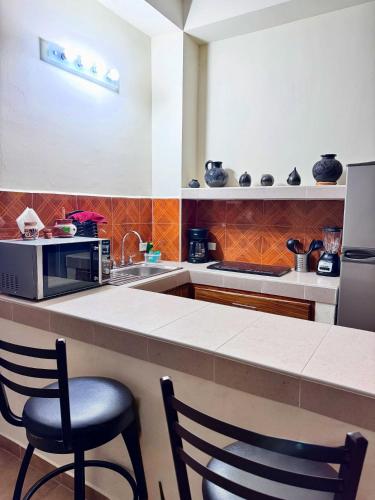 a kitchen with a counter with two chairs and a microwave at Apt María Villa Lorena in La Paz