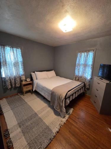 a bedroom with a bed and a dresser and two windows at The Nelson House in Winner