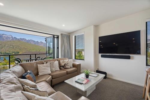 een woonkamer met een bank en een groot raam bij Remarkable Lake View in Queenstown
