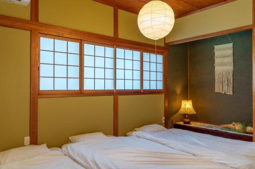 a bedroom with two beds and a lamp and windows at 民泊古都 in Takamatsu