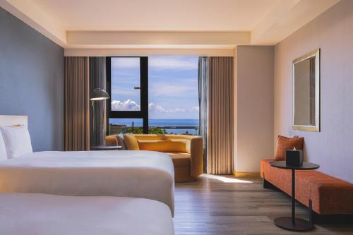 a hotel room with two beds and a couch and a window at Lakeshore Hotel Hualien in Hualien City