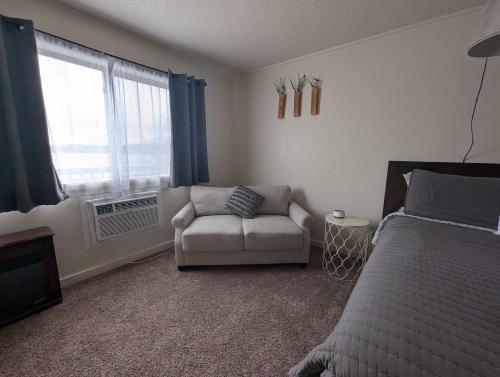 a bedroom with a bed and a couch and a window at Fife Lake Lodge Multi-Level Lake View King Suite in Fife Lake