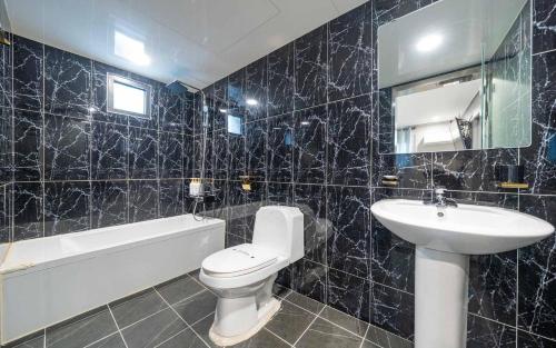 a black tiled bathroom with a sink and a toilet at On & Off Hotel in Incheon
