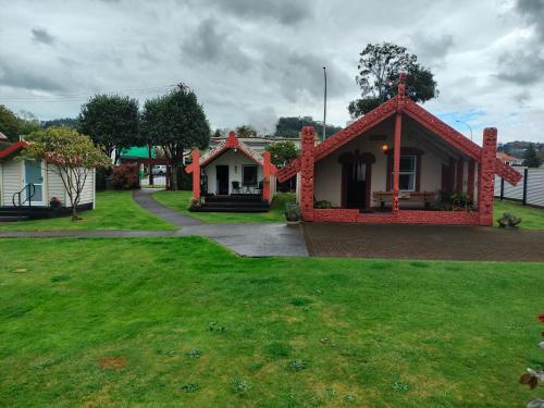 a small house with a red roof in a yard at Wharepai in Rotorua