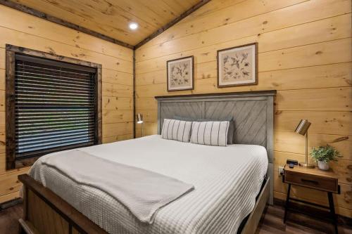 a bedroom with a bed in a room with wooden walls at New Cozy Mountain Chalet Hot Tub Near Downtown in Gatlinburg