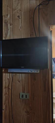 a flat screen tv sitting on top of a wooden cabinet at Como florcita en la mata in Villarrica