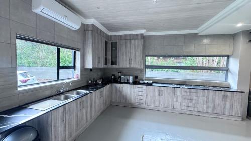 a kitchen with two sinks and two windows at Modern Retreat with Stylish Interiors & Peaceful Garden View in Bloemfontein