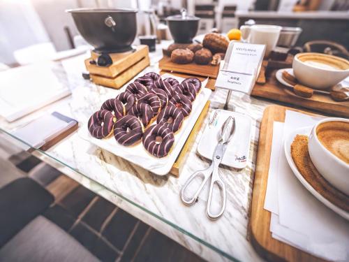 広州市にあるMehood Lestie International Hotel Linhexi Guangzhou East Railway Station Branch - Free Shuttle Bus to Canton Fair Complex During Canton Fair Period & Free Deliver Service to Guangzhou Baiyun International Airport & Free VPN Internet Accessのチョコレートドーナツやその他のペストリーが置かれたテーブル