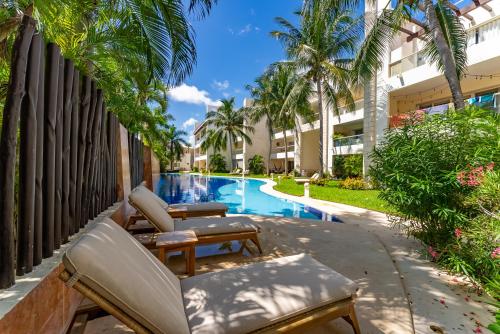 a resort pool with lounge chairs and palm trees at Spacious Apartment with Terrace, Pool and Beach Access in Puerto Aventuras