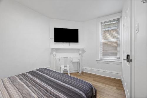 a bedroom with a bed and a desk and a television at Pittsburgh Shadyside 2B Stylish and Cozy Private Bedroom with Shared Bathroom in Pittsburgh
