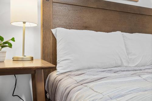 a bed with a wooden headboard and a table with a lamp at Pittsburgh Shadyside 2B Stylish and Cozy Private Bedroom with Shared Bathroom in Pittsburgh