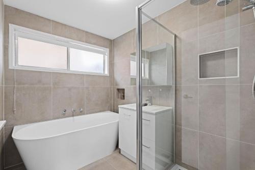 y baño con bañera blanca y ducha. en Seabreeze Retreat, en Portarlington