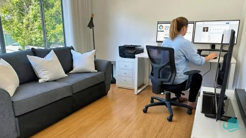 una mujer sentada en un escritorio en una oficina con un ordenador en WishStay Waterfront Luxury Retreat - private pool, en Morisset East