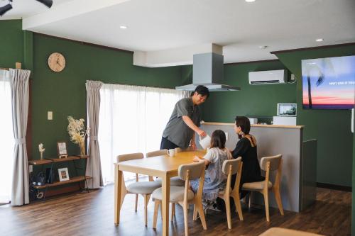 a man and two girls sitting at a table in a kitchen at 古民家の宿 Yamotas 馬籠 in Nakatsugawa