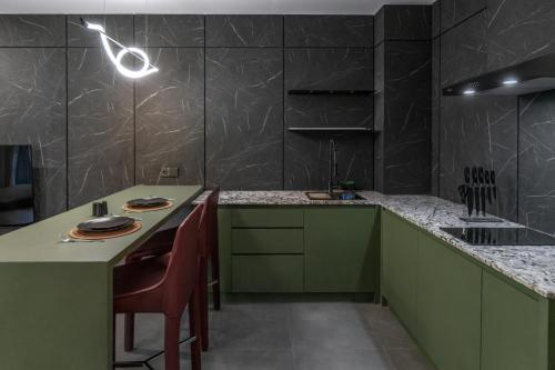 una cocina con armarios verdes y una mesa con sillas en XO Canggu adults only, en Canggu