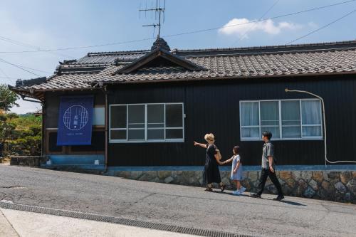 a family walking down a street in front of a house at 古民家の宿 Yamotas 馬籠 in Nakatsugawa