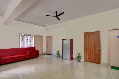 a living room with a red couch and a ceiling fan at Hotel O Tumpa Inn in Kolkata