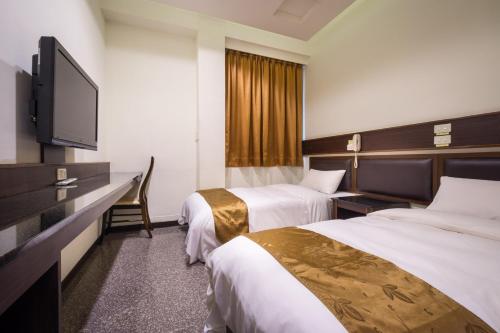 a hotel room with two beds and a flat screen tv at Twinstar Hotel in Taichung