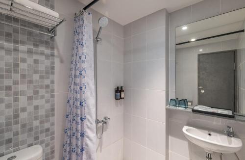 a white bathroom with a sink and a shower at GOLDEN TULIP ESSENTIAL PIK2 JAKARTA in Tangerang