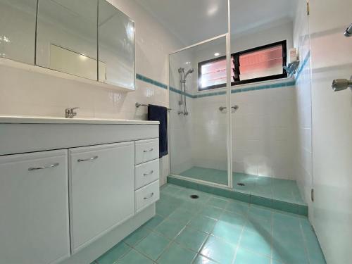 a white bathroom with a shower and a sink at A Beach Affair in Amity Point