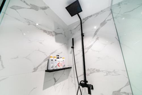 a shower in a bathroom with white marble walls at Chocolate Hotel Seongnam in Seongnam