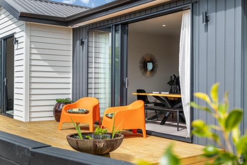 an outdoor patio with orange chairs and a table at Puhinui House in Warkworth
