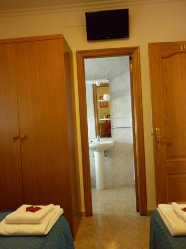 a bathroom with two beds and a bathroom with a sink at Pensión Portomiño in Portomarin