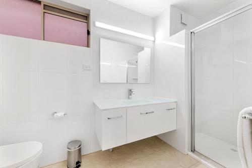 a white bathroom with a sink and a shower at Bay City (Geelong) Motel in Geelong