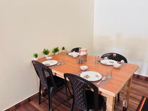 a table with black chairs and a wooden table with plates at Jim Corbett Guest House in Jhirna
