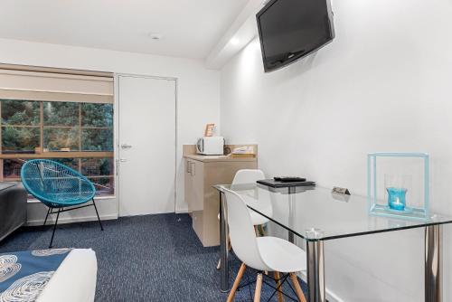 a living room with a glass table and chairs at Bay City (Geelong) Motel in Geelong