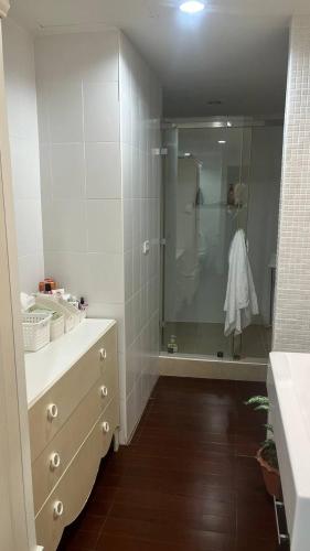a bathroom with a shower and a dresser with a mirror at Beachfront two bedroom apartment in Ban Nong Chaeng