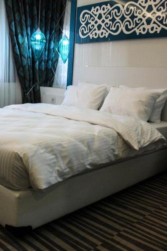 a large bed with white sheets and pillows at Grand Bursa Hotel in Bursa