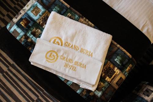 a towel with the name of a hotel on a bed at Grand Bursa Hotel in Bursa