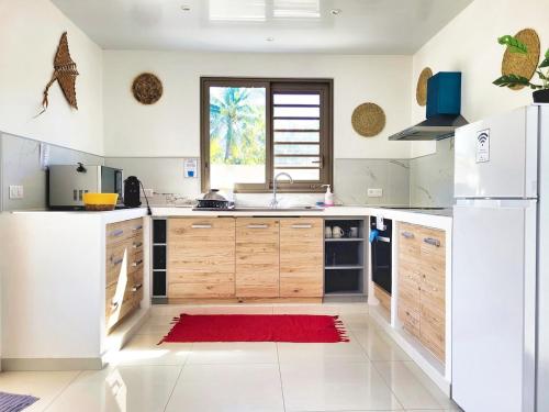 a kitchen with wooden cabinets and a red rug at Une pause au soleil et proche de la mer in Moorea