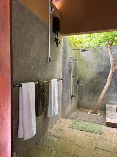a bathroom with white towels hanging on a wall at Village Verandah by Oshi in Dambulla