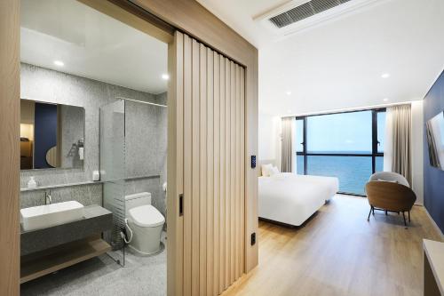 a bathroom with a bedroom with a bed and a sink at Pohang Hound Hotel Songdo Beach in Samgong