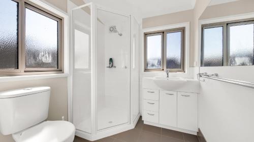 a white bathroom with a toilet and a sink at Cool Runnings in Dinner Plain