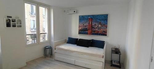 una habitación con un banco con una pintura en la pared en Appartement paisible, en Clichy