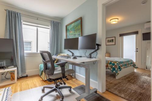 バークレーにあるBay Area Cozy Stays Berkeleyのデスク、コンピュータ、ベッドが備わる客室です。