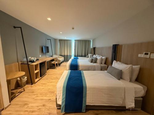 a hotel room with two beds and a television at Bella B Hotel in Nonthaburi