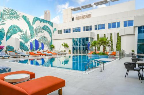 a resort pool with orange chairs and a building at Novotel Dubai World Trade Centre in Dubai